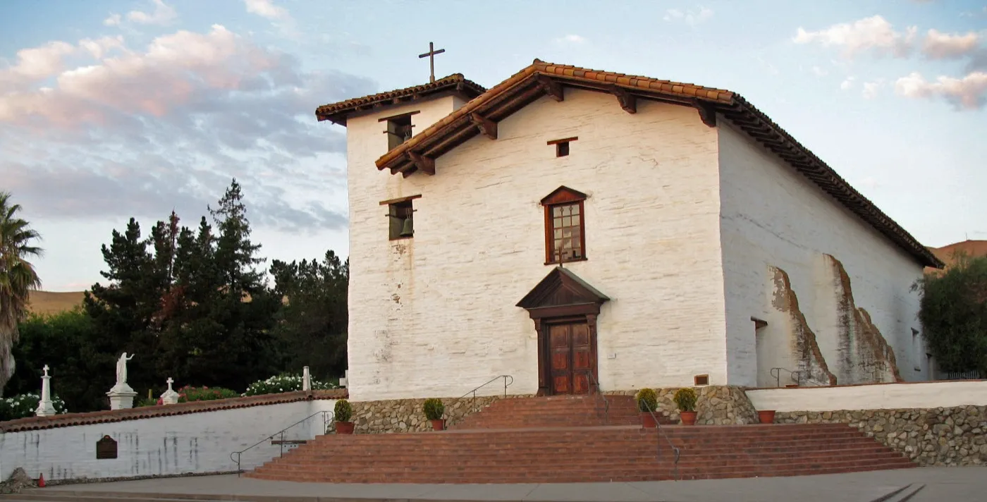 The white adobe facade and bell of the restored Mission San Jose church in Fremont, California